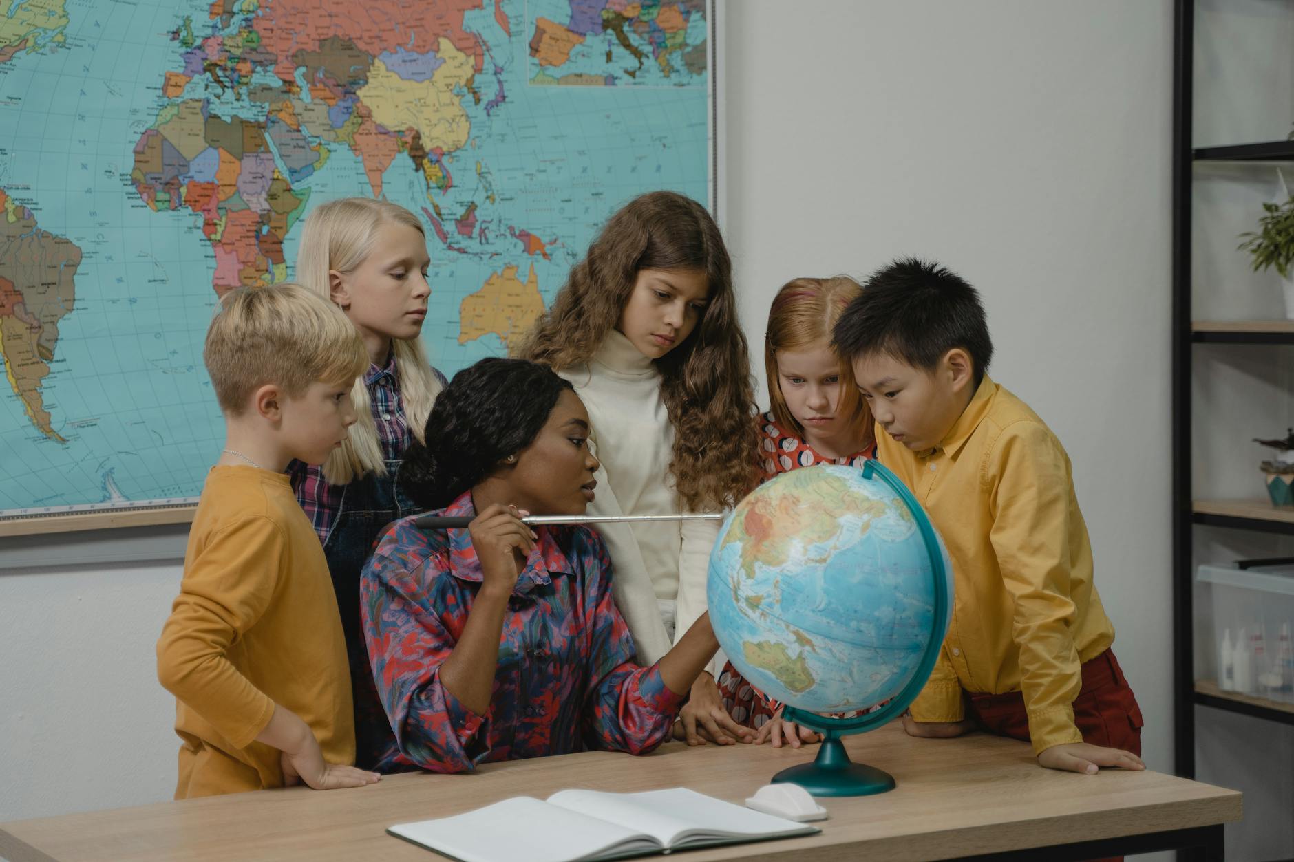Nauczyciel z dziećmi przy globusie na lekcji geografii w klasie Nauczyciel z dziećmi przy globusie na lekcji geografii w klasie