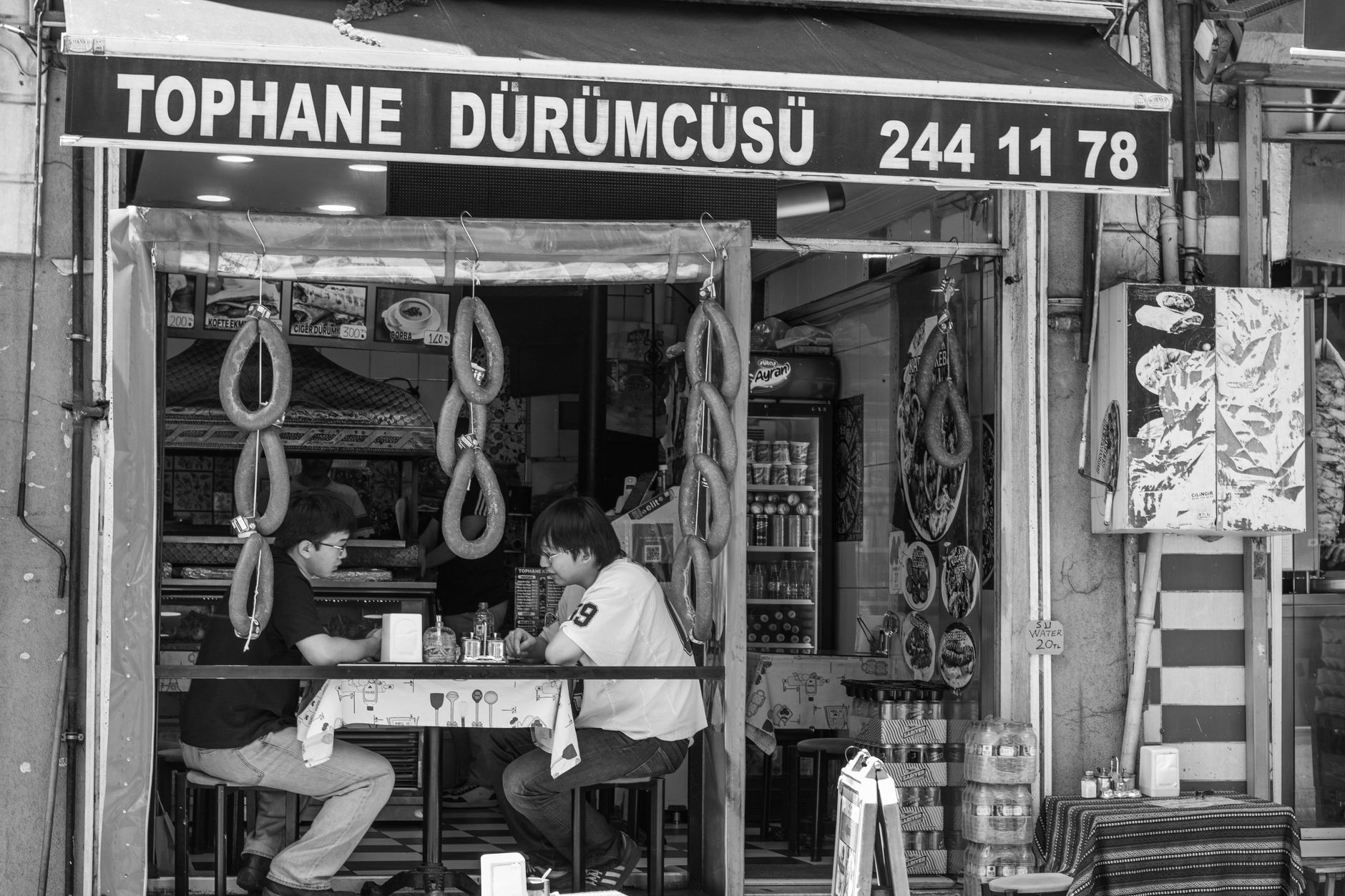 Ludzie jedzący dürümy w ulicznej knajpie Tophane Dürümcüsü