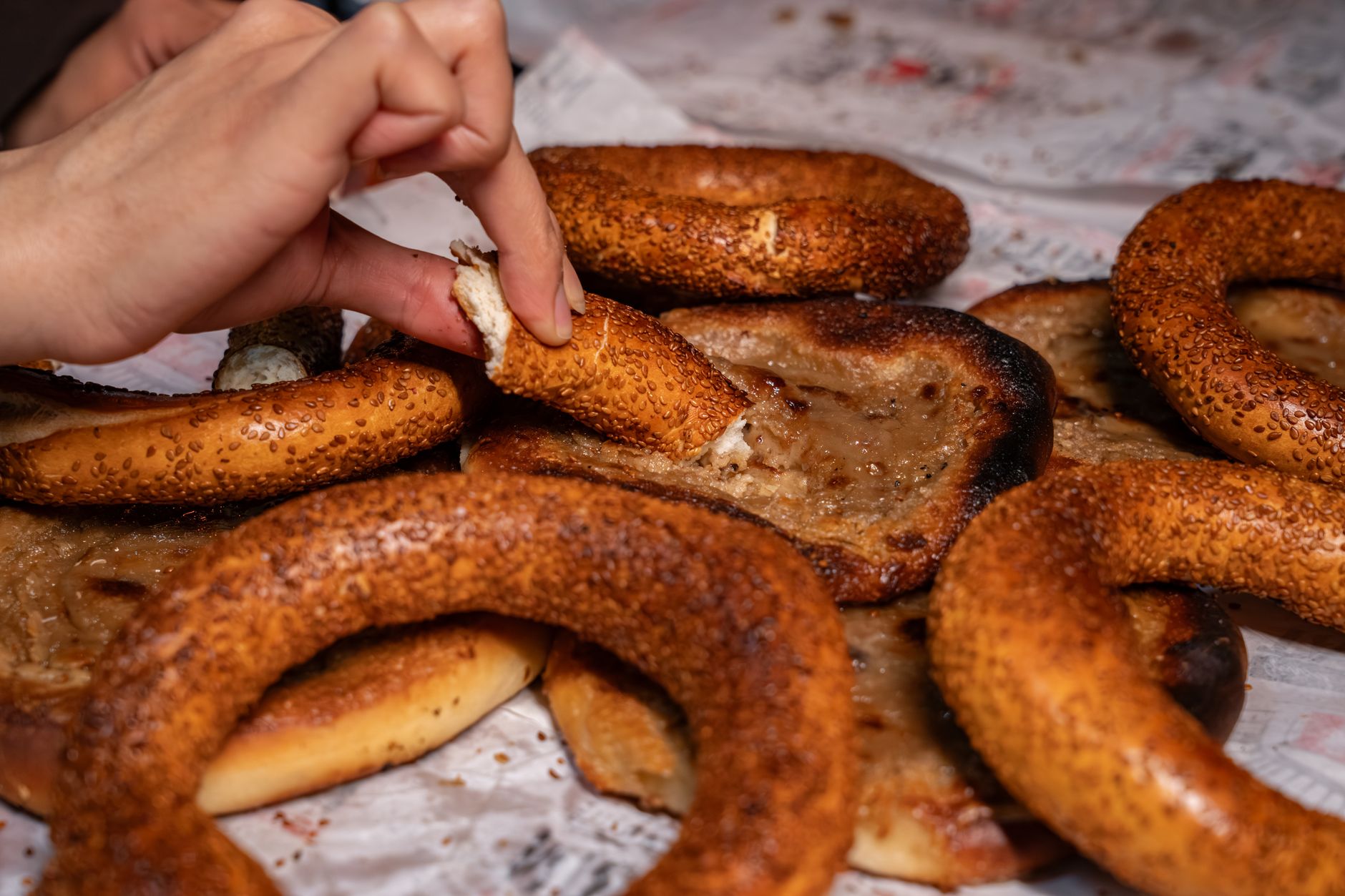 Ręka sięga po chrupiący simit na papierze, tani turecki street food